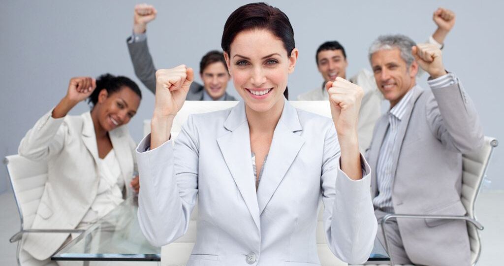 Happy business people celebrating a sucess with hands up in the office