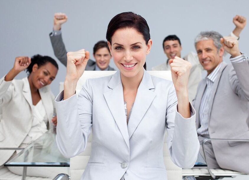 Happy business people celebrating a sucess with hands up in the office