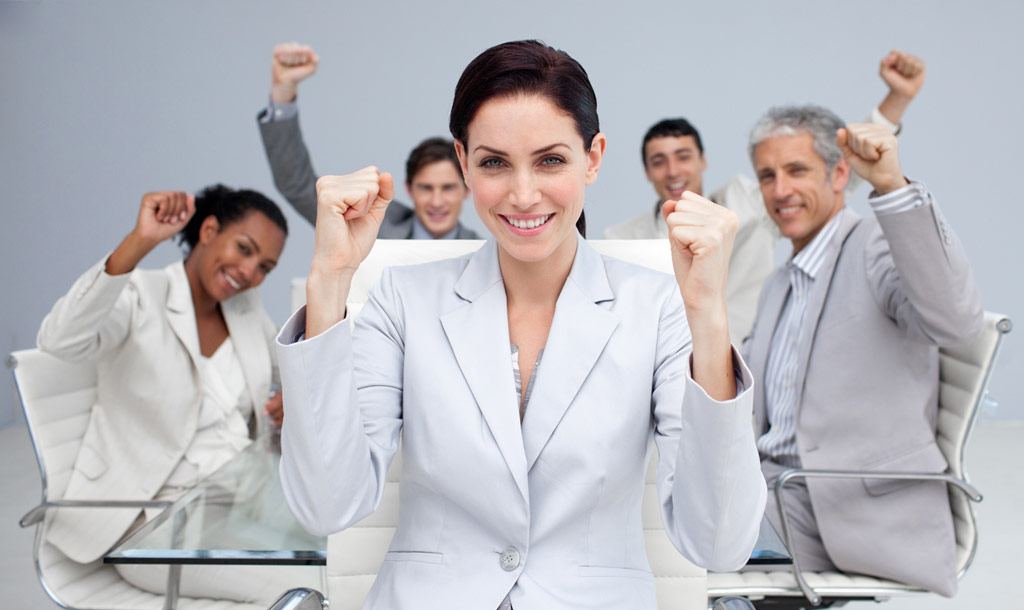 Happy business people celebrating a sucess with hands up in the office